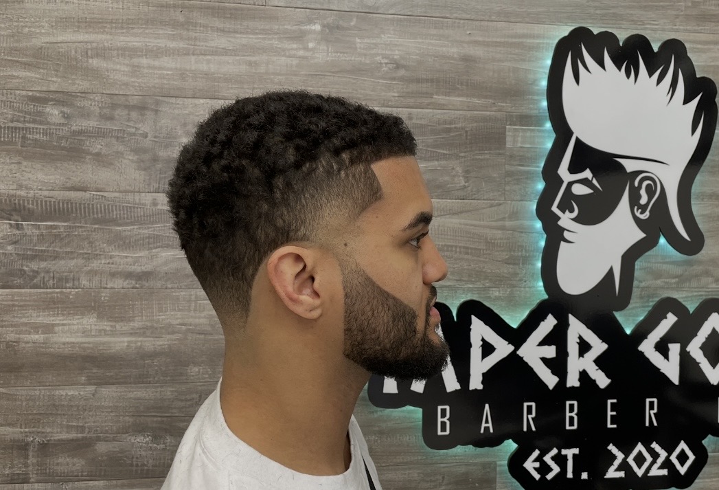 Clean taper haircut in front of the Taper Godz Barber Co. logo in Lakewood, CO